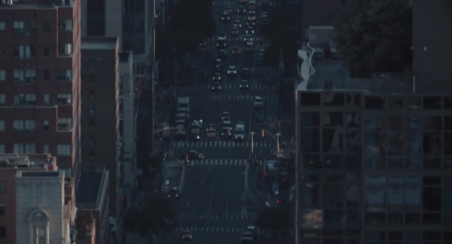 High-angle view tilts down on a busy New York City street with heavy traffic as dusk settles over the city