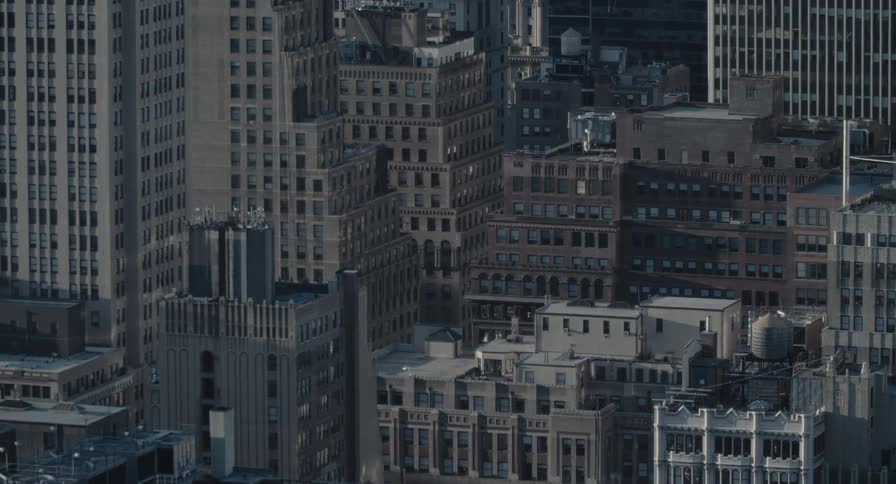 Sunlight and shadows move across the dense architecture of a major city in a moody time-lapse