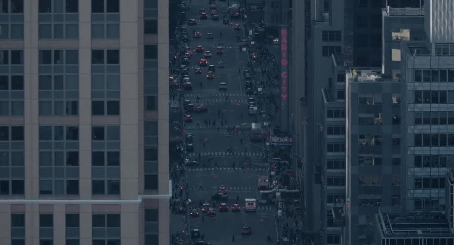 High-angle view of busy traffic and crowds of people on a street in Manhattan near Radio City Music Hall at dusk