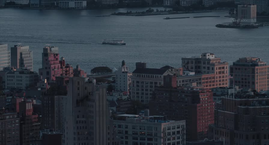 A serene high-angle view of a New York City cityscape at dusk as a ferry crosses the Hudson River