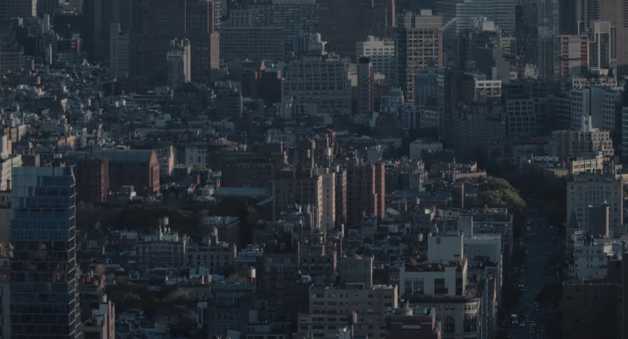 High-angle view of a dense New York City neighborhood with traffic moving through the streets in the morning light