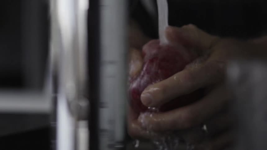 Person washes an apple at the sink