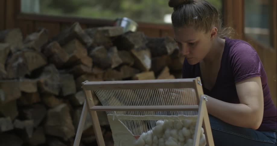 Woman working on a stringed art project on a frame