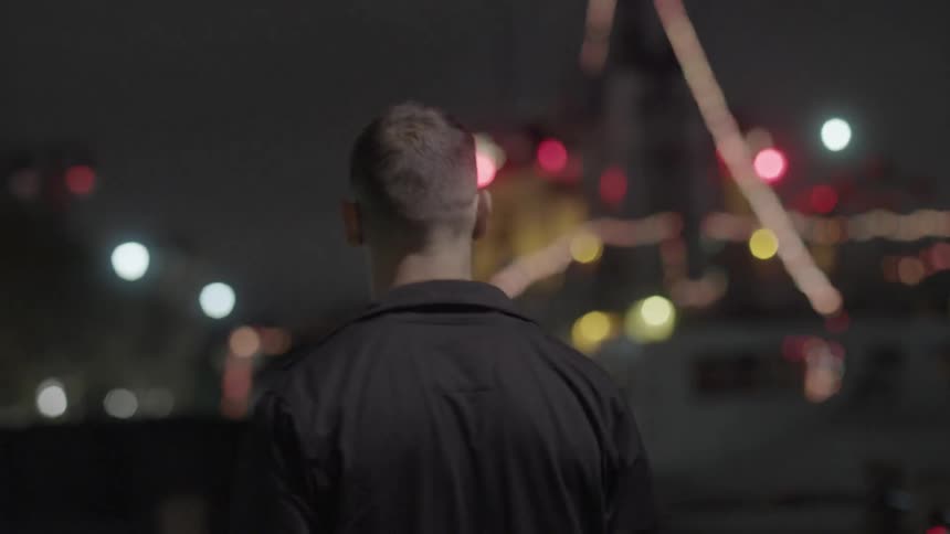 A man in a black shirt walks down the street at night