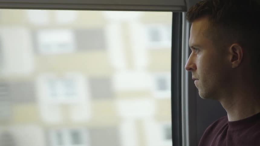 A man looks out the window of a moving vehicle