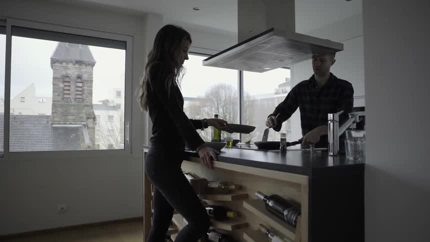 Man serving food from a pan to a woman's plate in an apartment