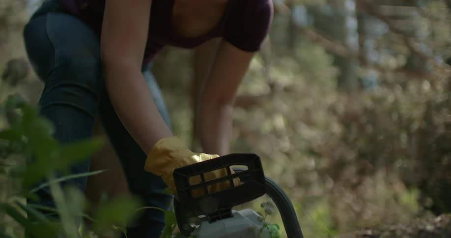 A woman is working cutting wood with a chainsaw