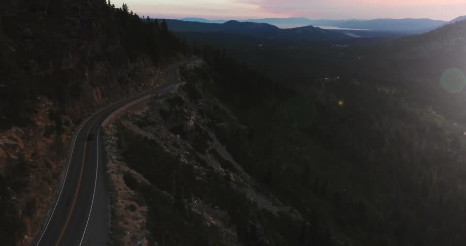 A long winding road sits on a mountain at sunset