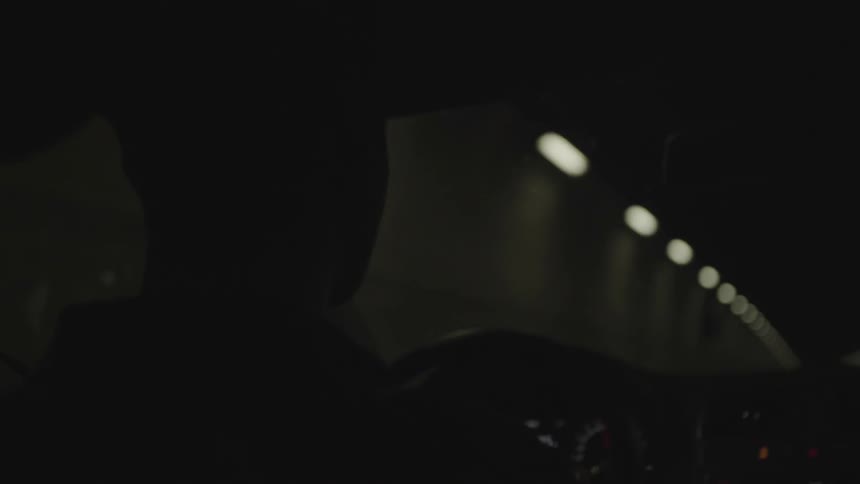 A person drives down a dark tunnel