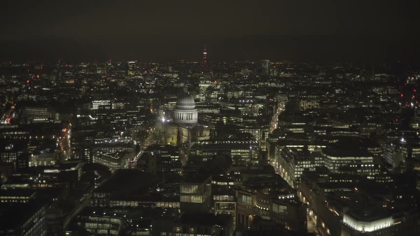 A domed building stands out amid city buildings at night