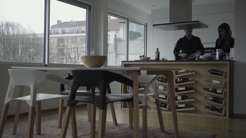 A couple scrape food from dishes in a kitchen