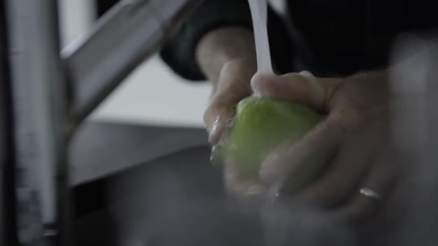 A person washes an apple in a kitchen