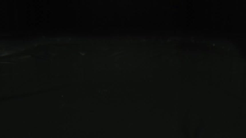 Close-up of dark water reacting to sound waves and forming abstract patterns in slow motion
