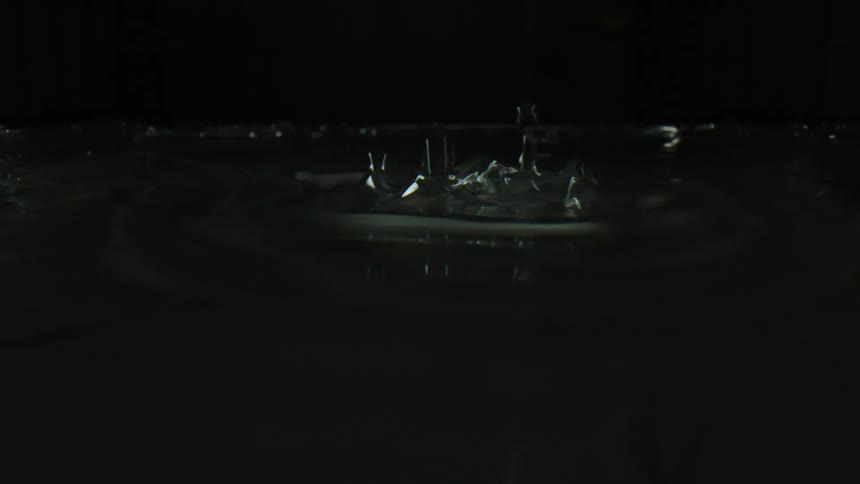 A dramatic super slow-motion close-up of water splashing and churning against a stark black background