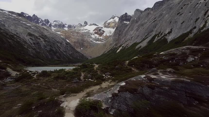 Snow covers the peaks of mountains rising above a lake