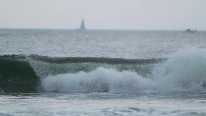 Two boats far out into the ocean with waves splashing