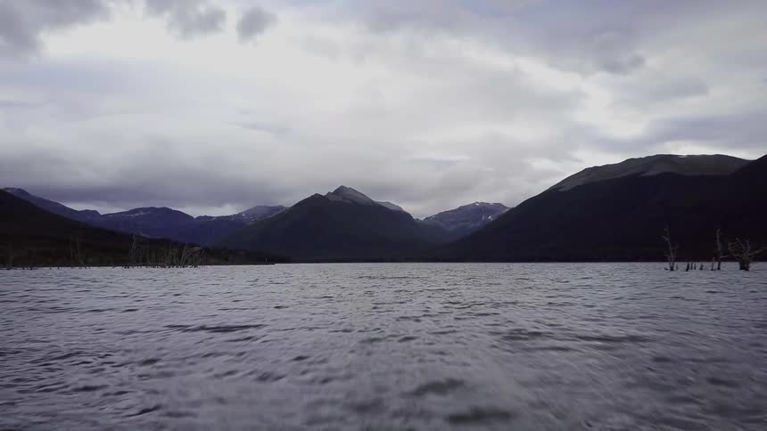 A body of water at the base of some mountains on a cloudy day