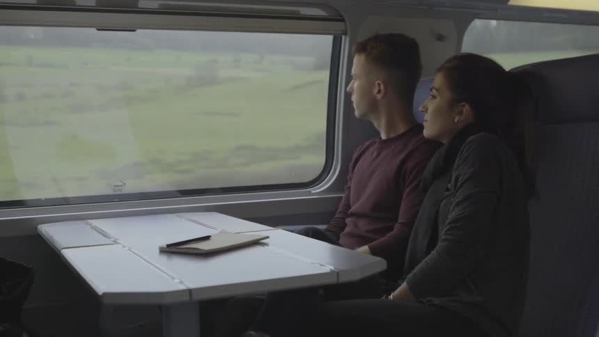 Man and woman traveling on train looking out window