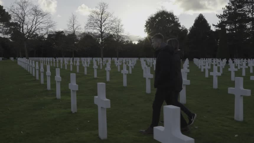 A man and woman walk through a cemetery