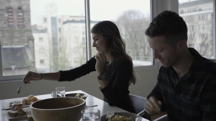 Man and woman eating at a table with a city in the background