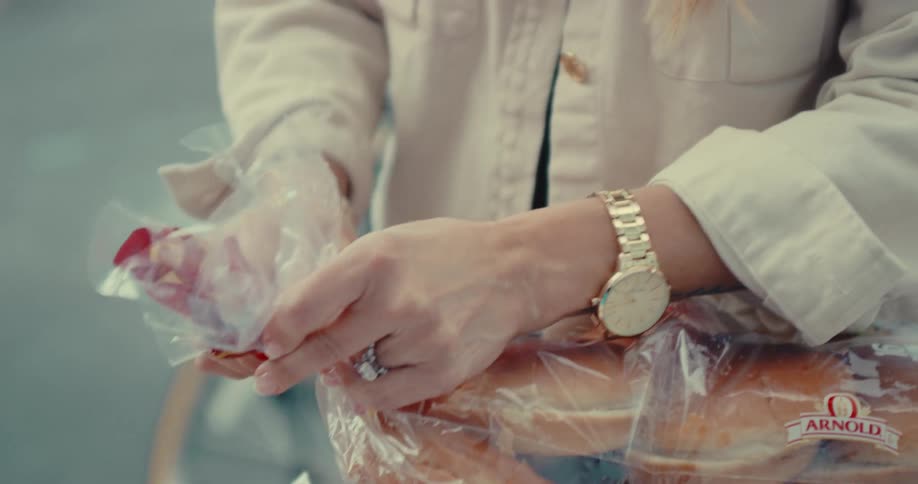 Close up shot of a woman's hands untwisting the plastic tie on a bag of hamburger buns