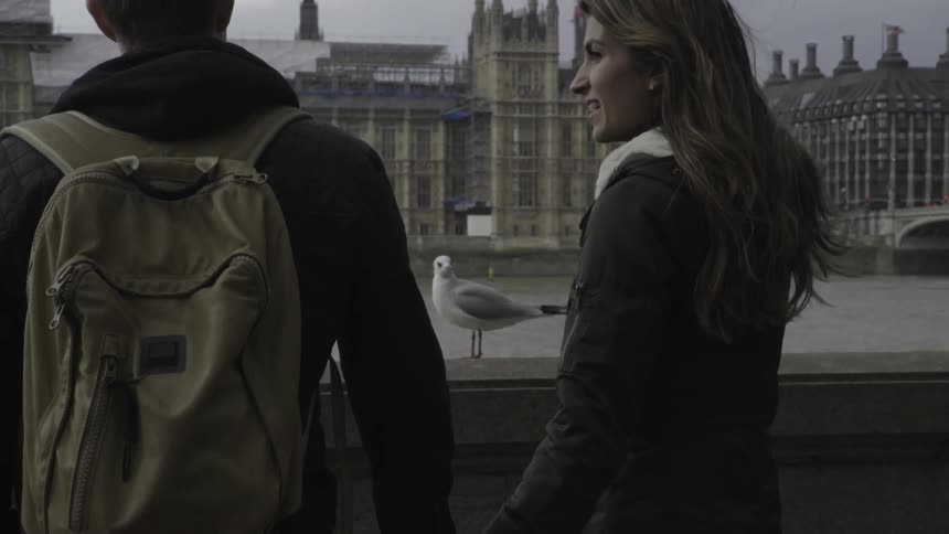 A man and woman hold hands while looking at city buildings