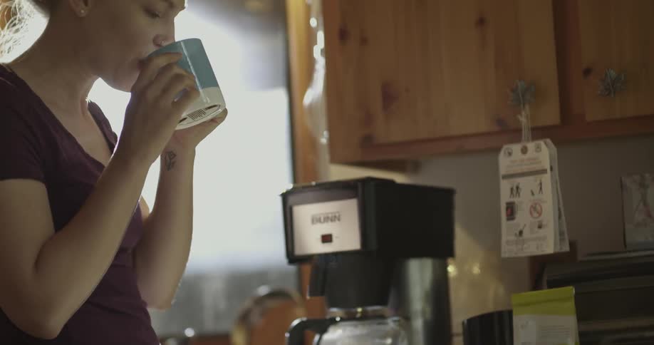 A woman takes a sip from a hot cup of coffee