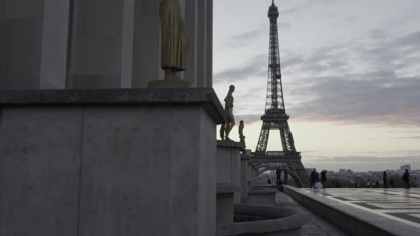 Several people standing on a rooftop near the eiffel tower