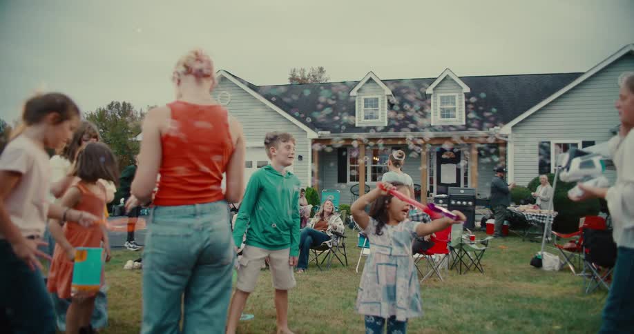 Footage of a group of children having fun with bubbles at a lively backyard party