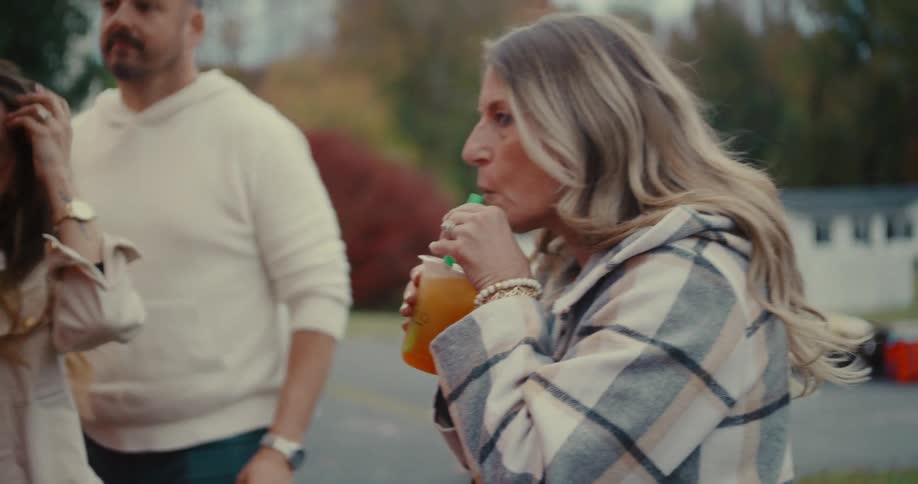 Slow motion shot of a woman handing a refreshing drink to her friend at an outdoor gathering