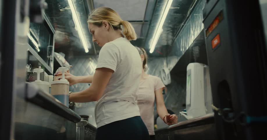 A worker in a food truck carefully prepares a boba tea drink in slow motion