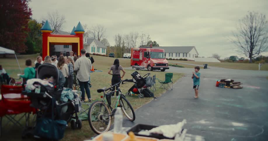 Families and neighbors gather for a fun community block party with a bouncy castle and a red food truck