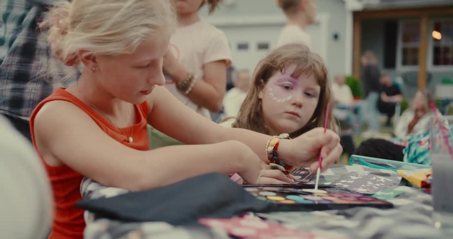 Creative kids enjoy face painting together during a backyard summer gathering
