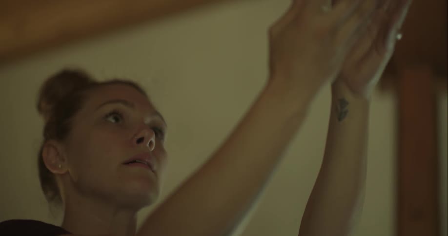 A woman is carefully changing a lightbulb in a fixture