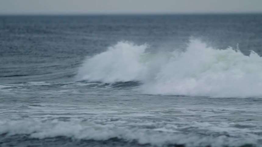 A wave crashes toward the shore