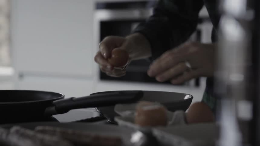 A person cracks an egg into a pan