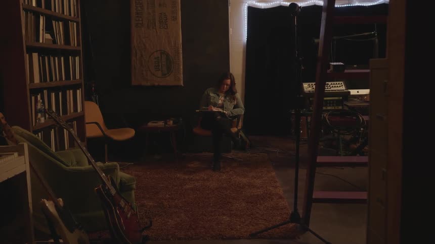 A woman is sitting in a room alone reading a book
