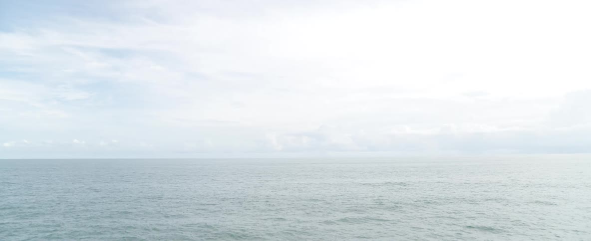 A serene and minimalist view of the calm ocean under a bright, overcast sky