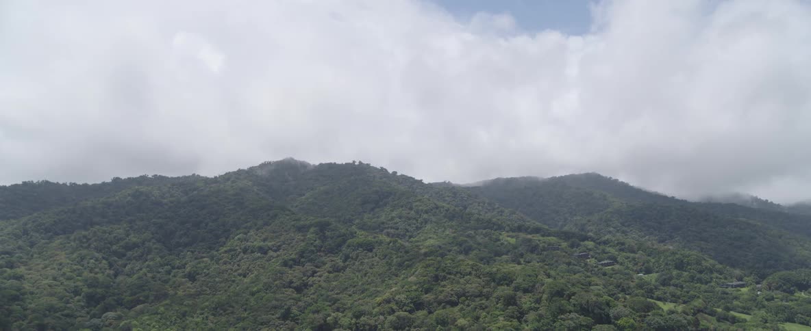 A beautiful landscape view of a tropical mountain range with clouds hanging low over the peaks