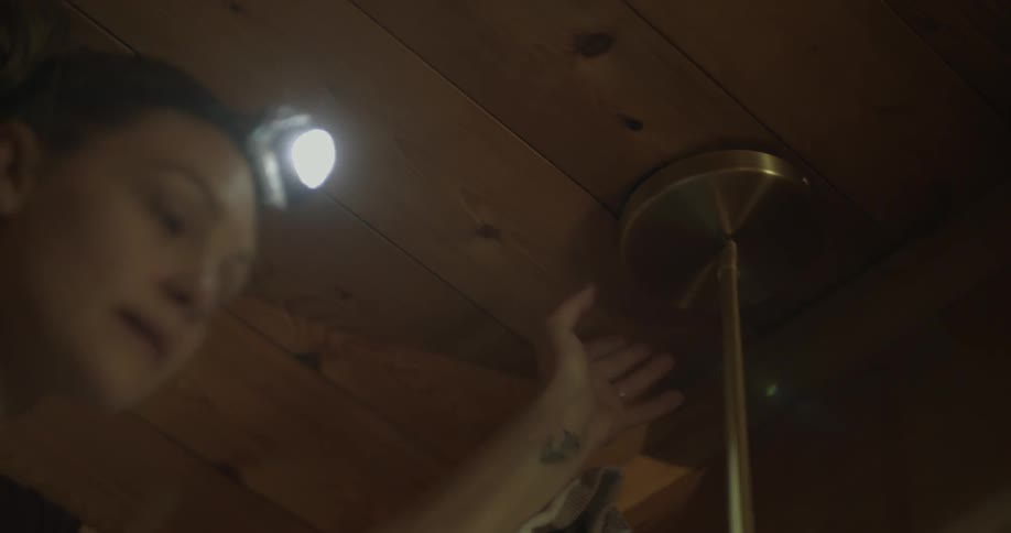 A woman screws a light fixture in place