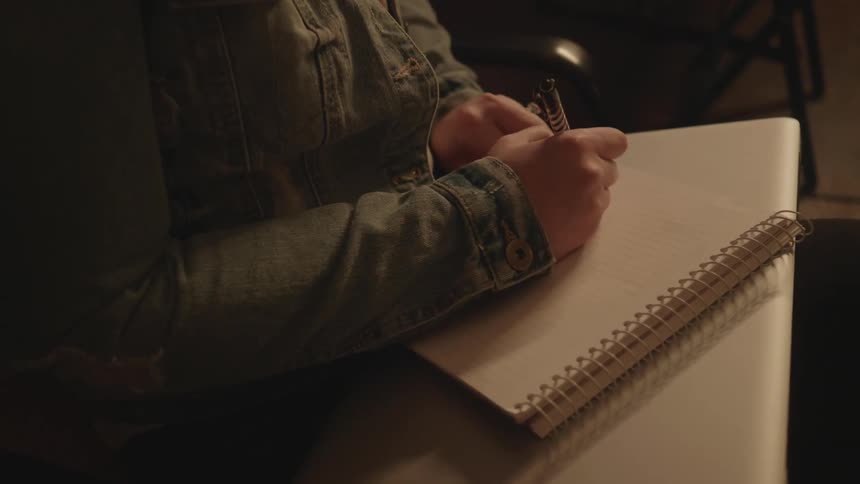 Person writing in a notebook with a pen