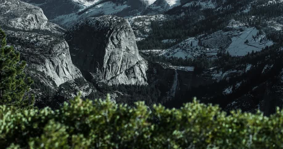 Clouds and shadow move over half dome and a waterfall in yosemite during winter