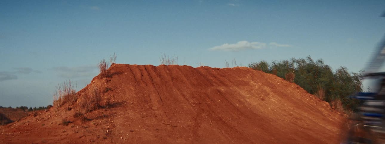 A motocross rider launches off a dirt jump and soars through the air in dramatic slow motion