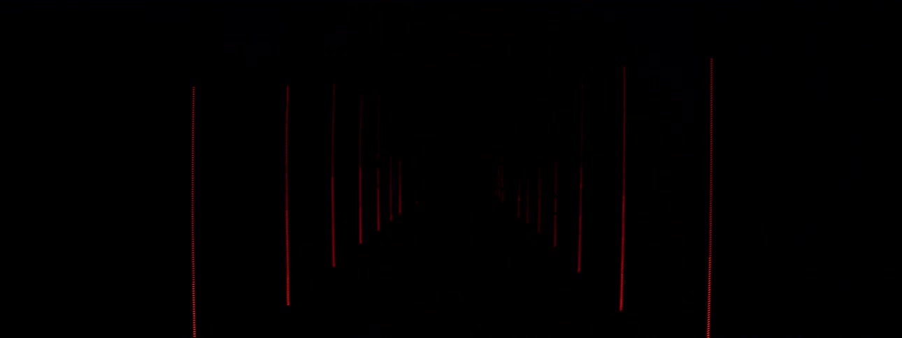 A motocross rider is dramatically revealed in a smoky, futuristic hallway illuminated by flashing red and white neon lights