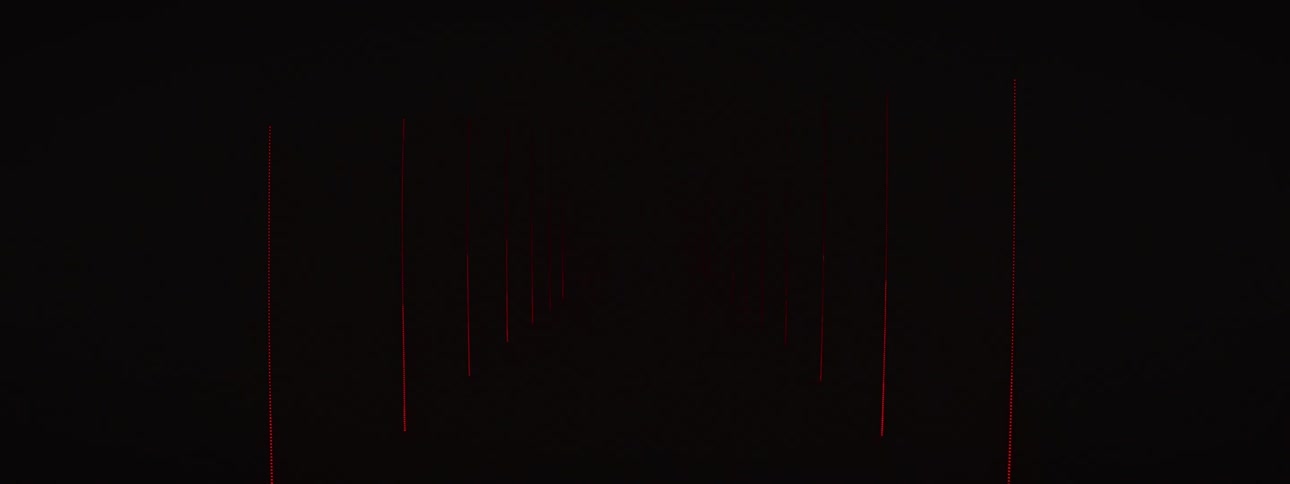 A motocross racer in full gear stands in a futuristic tunnel of flashing, strobing neon lights and smoke