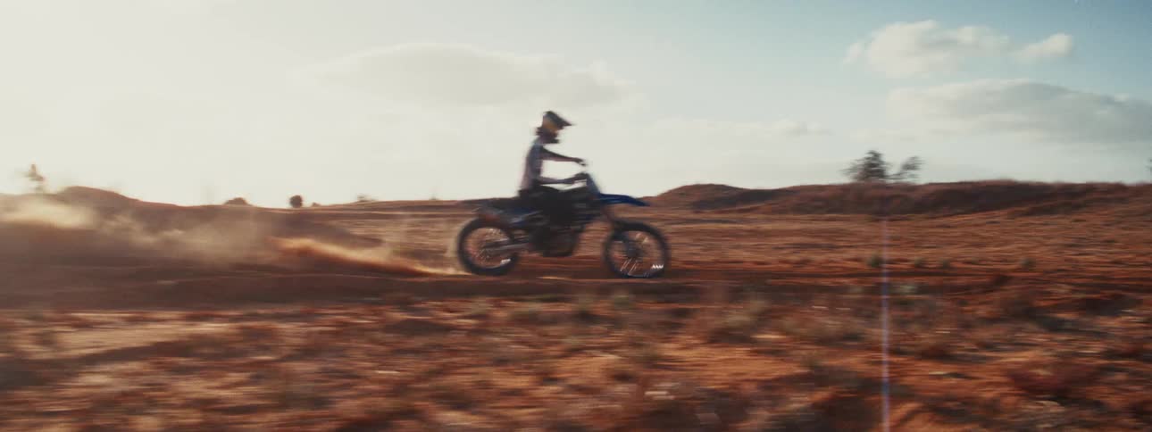 A motocross rider performs impressive jumps in slow motion on a dusty desert track