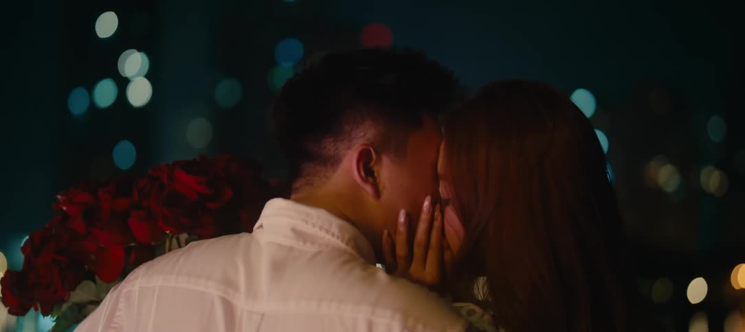 A young couple enjoys a romantic moment, kissing passionately on a date with a beautiful city light bokeh background