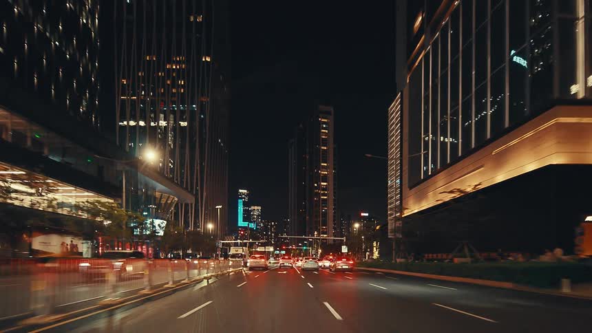 A smooth point-of-view drive through a vibrant, modern city at night surrounded by brightly lit skyscrapers