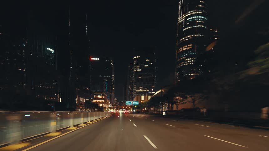 A point-of-view drive through a modern metropolis at night, gliding under an architectural overpass towards a glowing skyline of skyscrapers