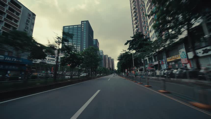 A dynamic first-person point-of-view drive emerging from under an overpass onto a wide street in a modern Asian city